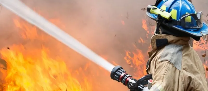 first responder discount Firefighter spraying water on flames, highlighting the Tax Scout first responder tax discount