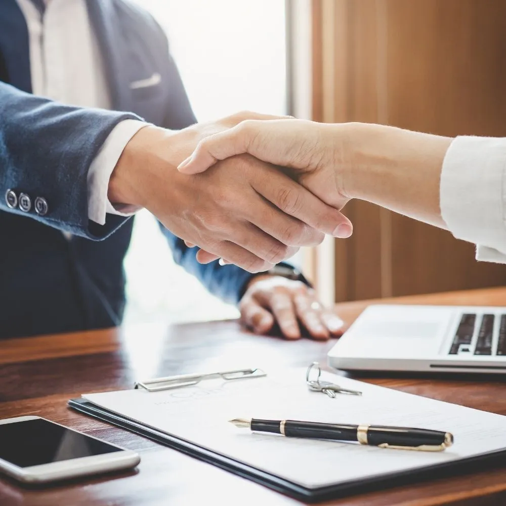 tax scout services Handshake over a desk with a laptop and documents representing Tax Scout tax services